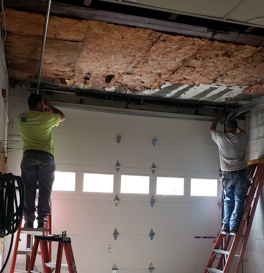 Two Spartan Garage Doors technicians on ladders installing a new white insulated garage door in Pittsburgh